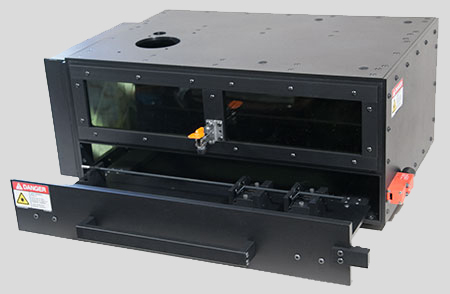 An enclosure made of black anodized aluminum plates, with a laser-safe front window and a sliding front door with an internal platform for holding devices to be laser marked. It looks like Darth Vader's toaster oven.